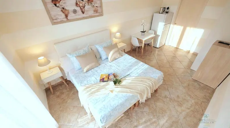 Une chambre lumineuse avec un lit double et une petite table.