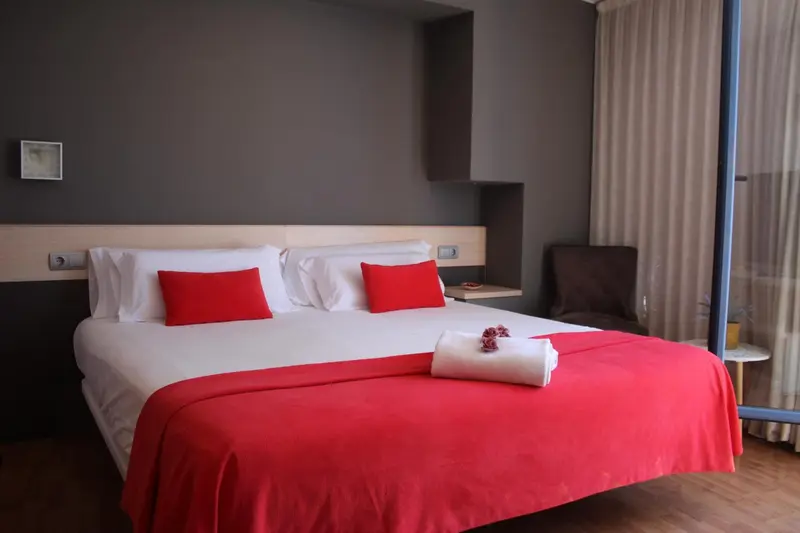 Une chambre avec un grand lit recouvert d'une courtepointe rouge et de coussins.