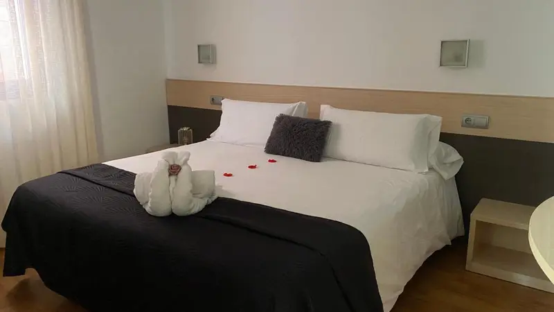 Lit double préparé avec soin dans une chambre lumineuse.