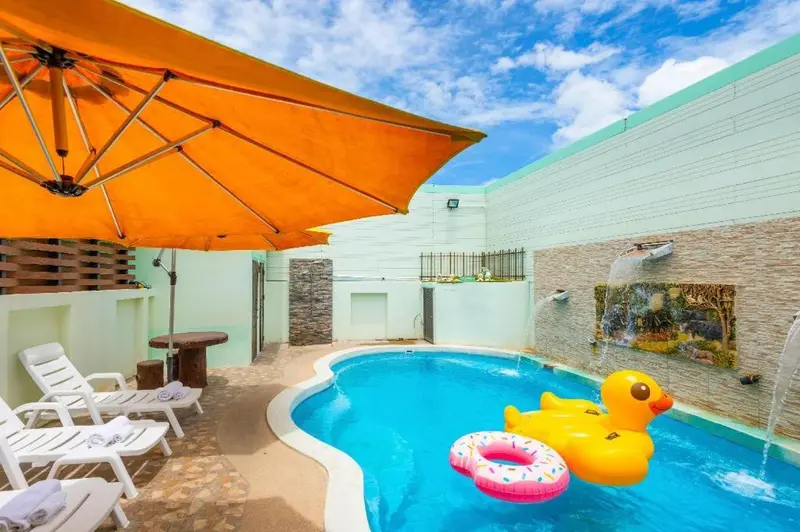 Petite piscine en extérieur avec transats et parasol orange.