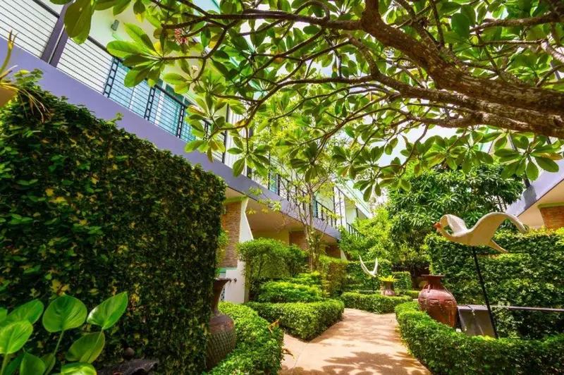 Jardin luxuriant avec allée et sculpture d'oiseau.