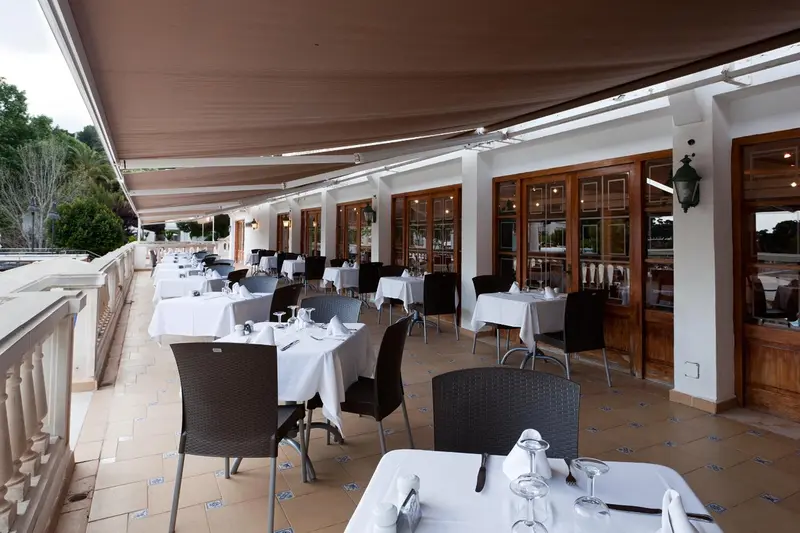 Terrasse ombragée avec tables nappées et chaises.