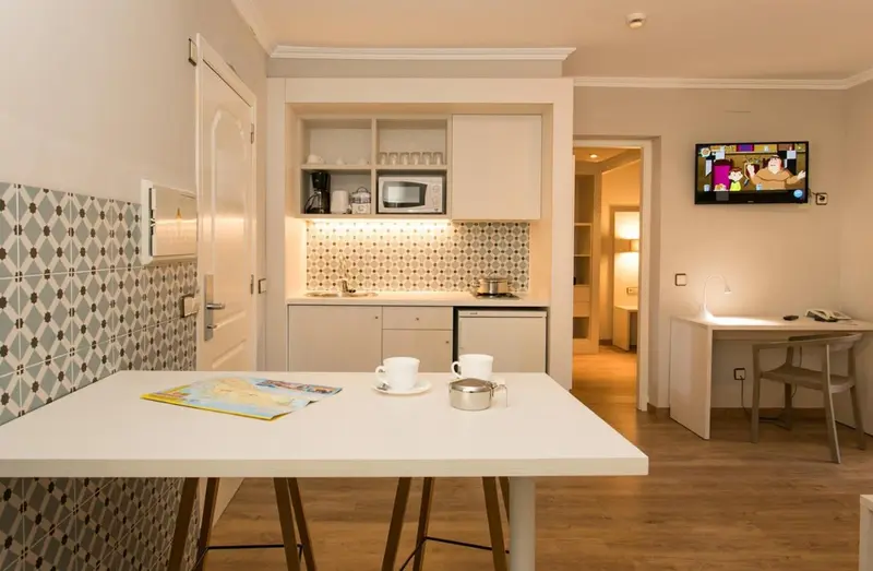 Une kitchenette lumineuse s'ouvre sur un espace repas et un salon.