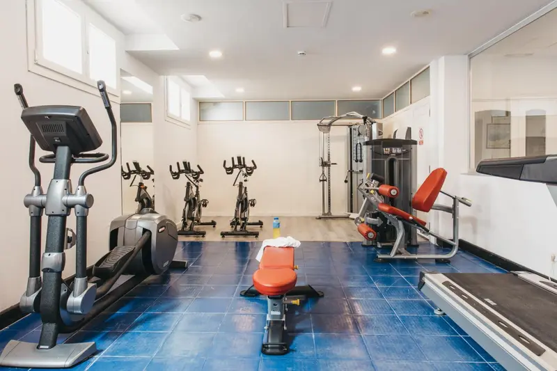 Une salle de sport lumineuse avec plusieurs appareils de musculation et de cardio.