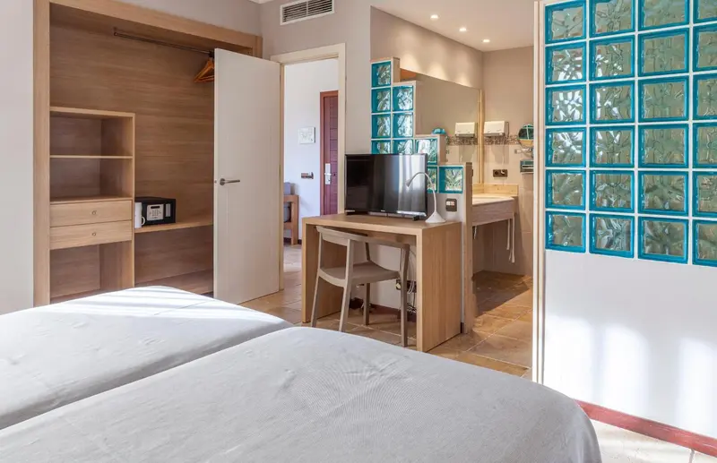 Une chambre lumineuse avec deux lits et un espace bureau.