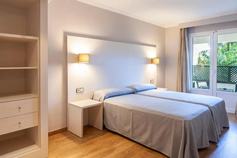 Une chambre lumineuse avec deux lits simples et un accès à une terrasse.