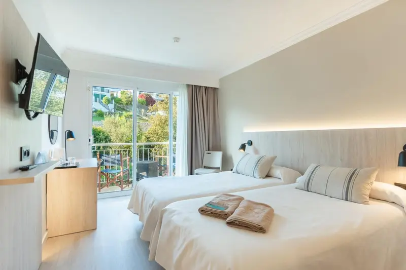 Une chambre lumineuse avec deux lits simples et un accès à un balcon.