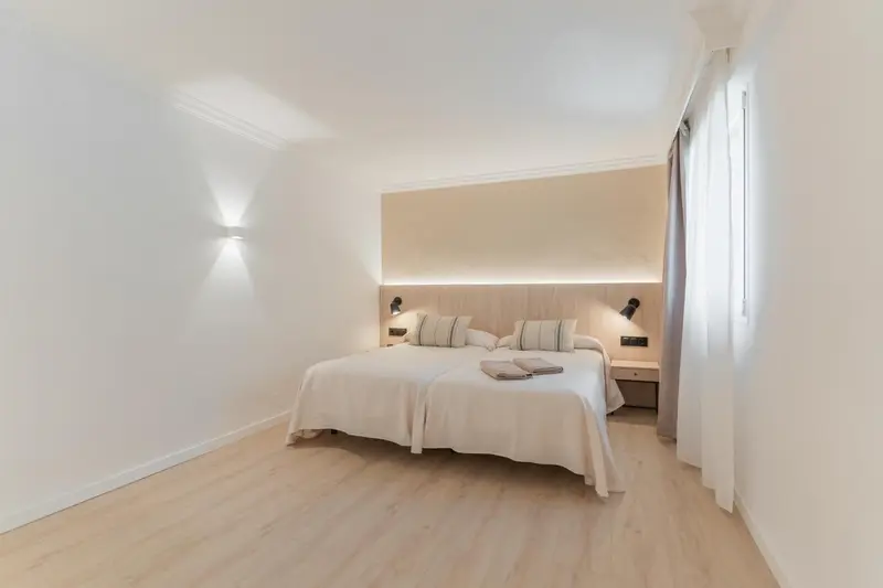 Une chambre lumineuse avec un grand lit recouvert de linge blanc.