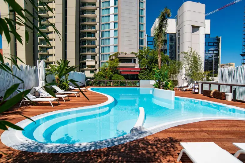 Piscine extérieure avec terrasse en bois et chaises longues.
