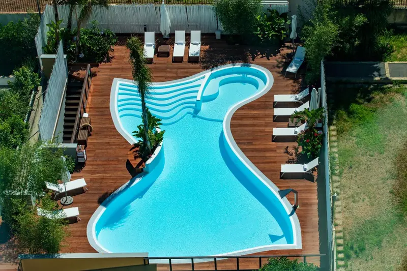 Vue aérienne d'une piscine aux formes organiques entourée d'une terrasse en bois.