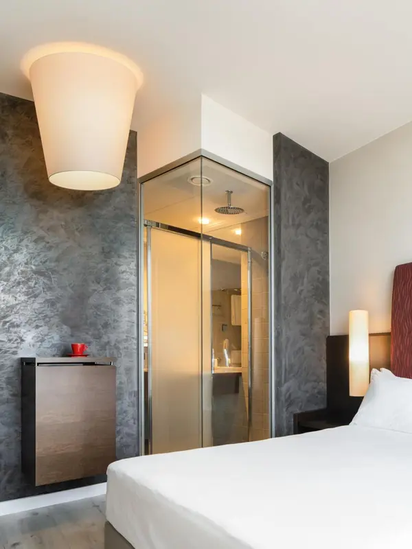Une chambre moderne avec un lit blanc et une douche vitrée.