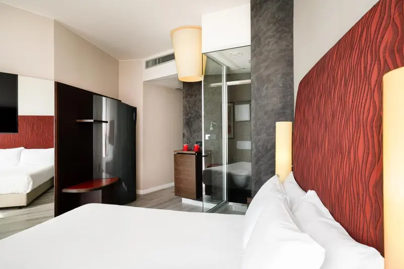Chambre moderne avec un grand lit et une salle de bain vitrée.