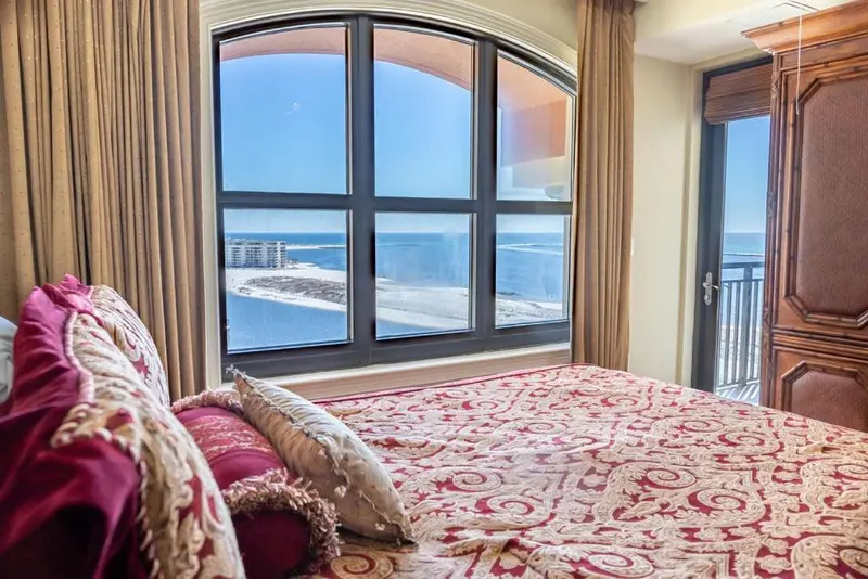 Une vue sur la mer est visible depuis une chambre avec un grand lit.