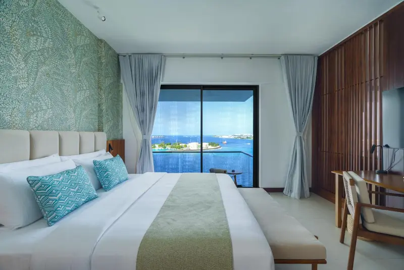Une chambre lumineuse avec un grand lit donnant sur la mer.