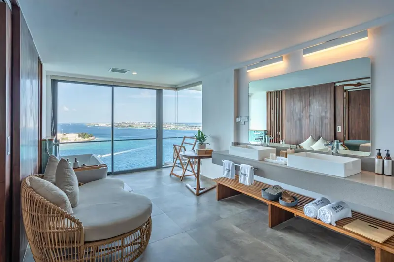 Une chambre lumineuse avec une grande baie vitrée donnant sur la mer.