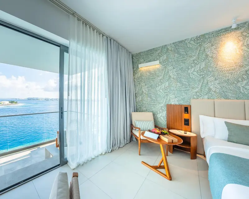 Chambre lumineuse avec vue sur la mer par de grandes baies vitrées.
