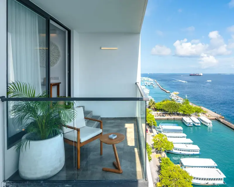 Une terrasse avec mobilier d'extérieur offre une vue sur la mer et un port de plaisance.