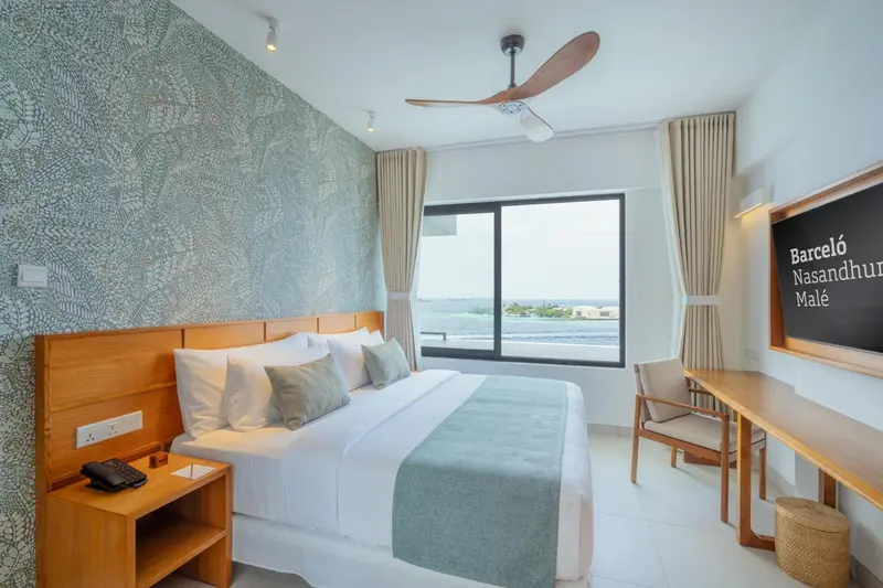 Chambre lumineuse avec un grand lit et une vue sur la mer.