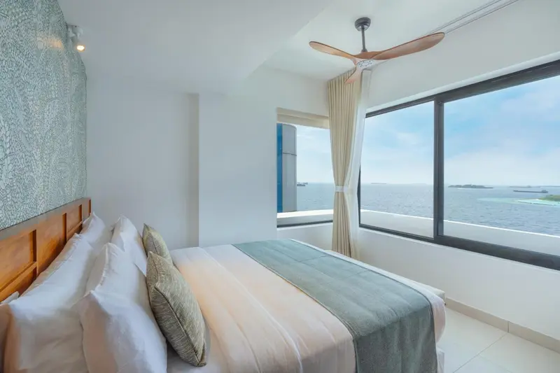 Chambre lumineuse avec un grand lit et vue sur la mer.