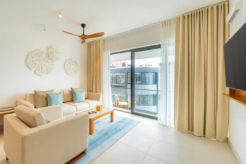 Un salon clair avec canapé et accès à un balcon.