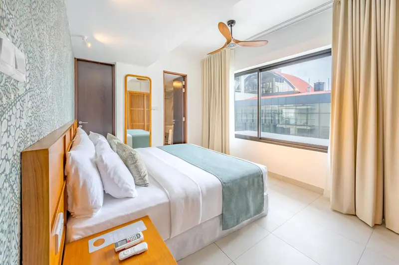 Chambre lumineuse avec un grand lit et une fenêtre donnant sur l'extérieur.
