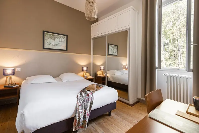 Une chambre lumineuse avec un lit double et un bureau.