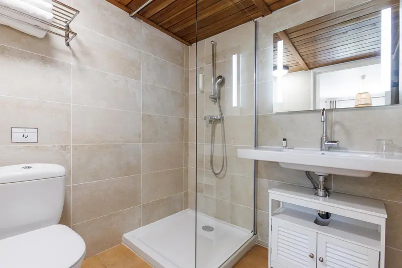 Une salle de bain moderne avec douche à l'italienne et vasque blanche.