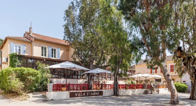 Bâtiment à l'architecture provençale avec une terrasse ombragée et des parasols.