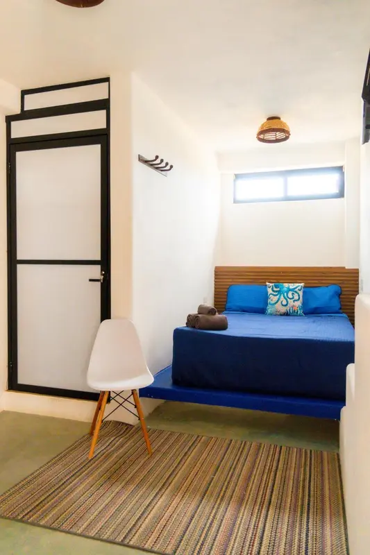 Une chambre lumineuse avec un lit recouvert d'une courtepointe bleue et de coussins.