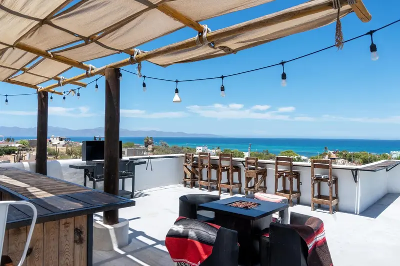 Terrasse ombragée avec mobilier de jardin et vue sur la mer.