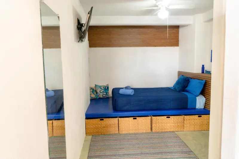 Une chambre lumineuse avec un lit intégré et des coussins bleus.