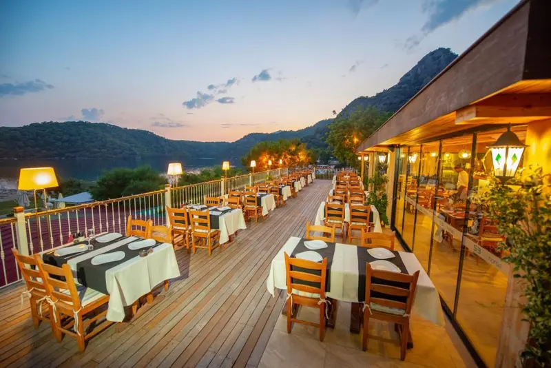 Terrasse de restaurant avec tables dressées face à un paysage montagneux.