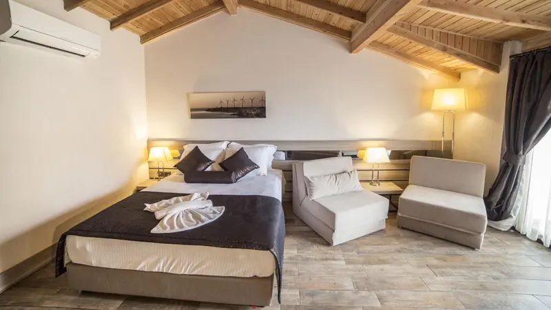 Une chambre lumineuse avec un grand lit et un coin salon.