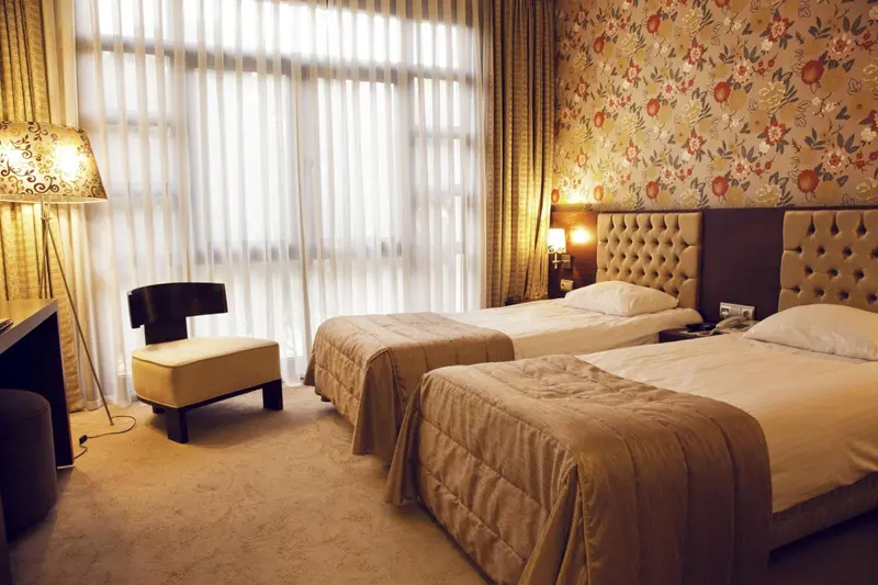 Une chambre d'hôtel avec deux lits simples et un fauteuil.