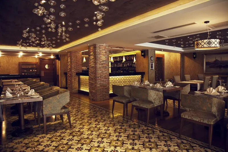 Une salle de restaurant élégante avec des tables dressées et un bar éclairé.