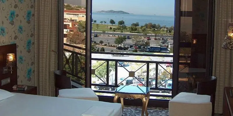 Une chambre d'hôtel lumineuse offre une vue dégagée sur la mer et le paysage environnant.
