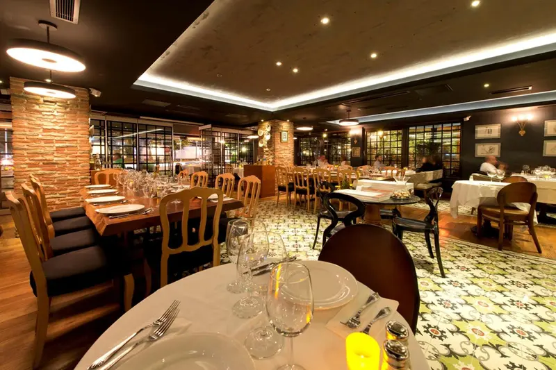 Une salle de restaurant lumineuse avec des tables dressées et un sol carrelé.