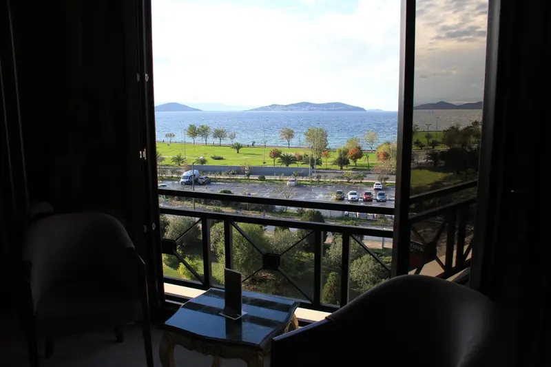 Vue sur la mer depuis un balcon avec des fauteuils et une table.