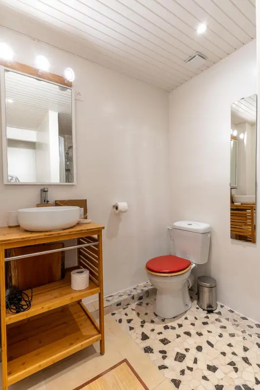 Une salle de bain lumineuse avec un lavabo en bois et des motifs géométriques au sol.