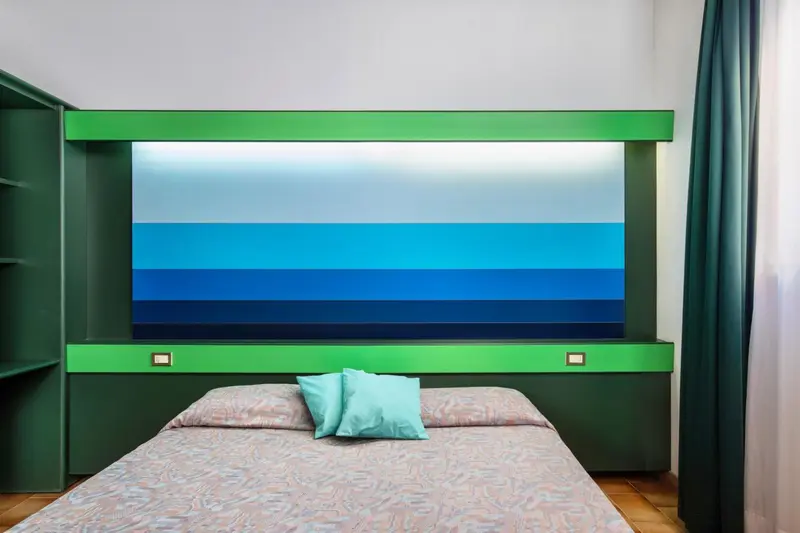 Une chambre avec un grand tableau représentant une vue marine au-dessus du lit.