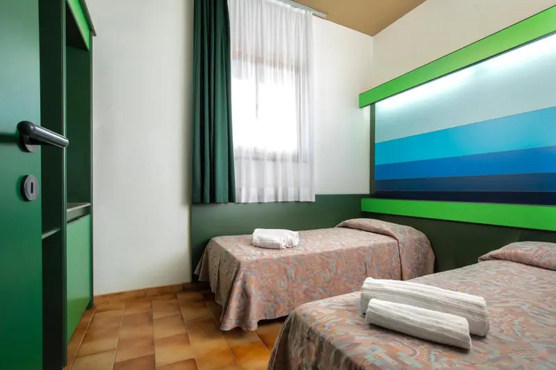 Chambre avec deux lits simples et une fenêtre drapée.