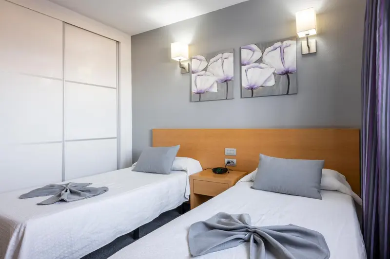 Une chambre avec deux lits simples et une décoration florale au mur.