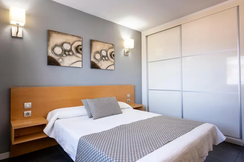 Une chambre lumineuse avec un grand lit et des tableaux décoratifs.