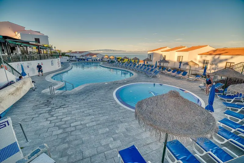 Piscine d'hôtel avec transats et parasols au bord de la mer.