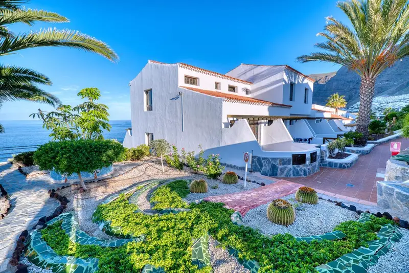 Bâtiment blanc avec végétation luxuriante et vue sur la mer.