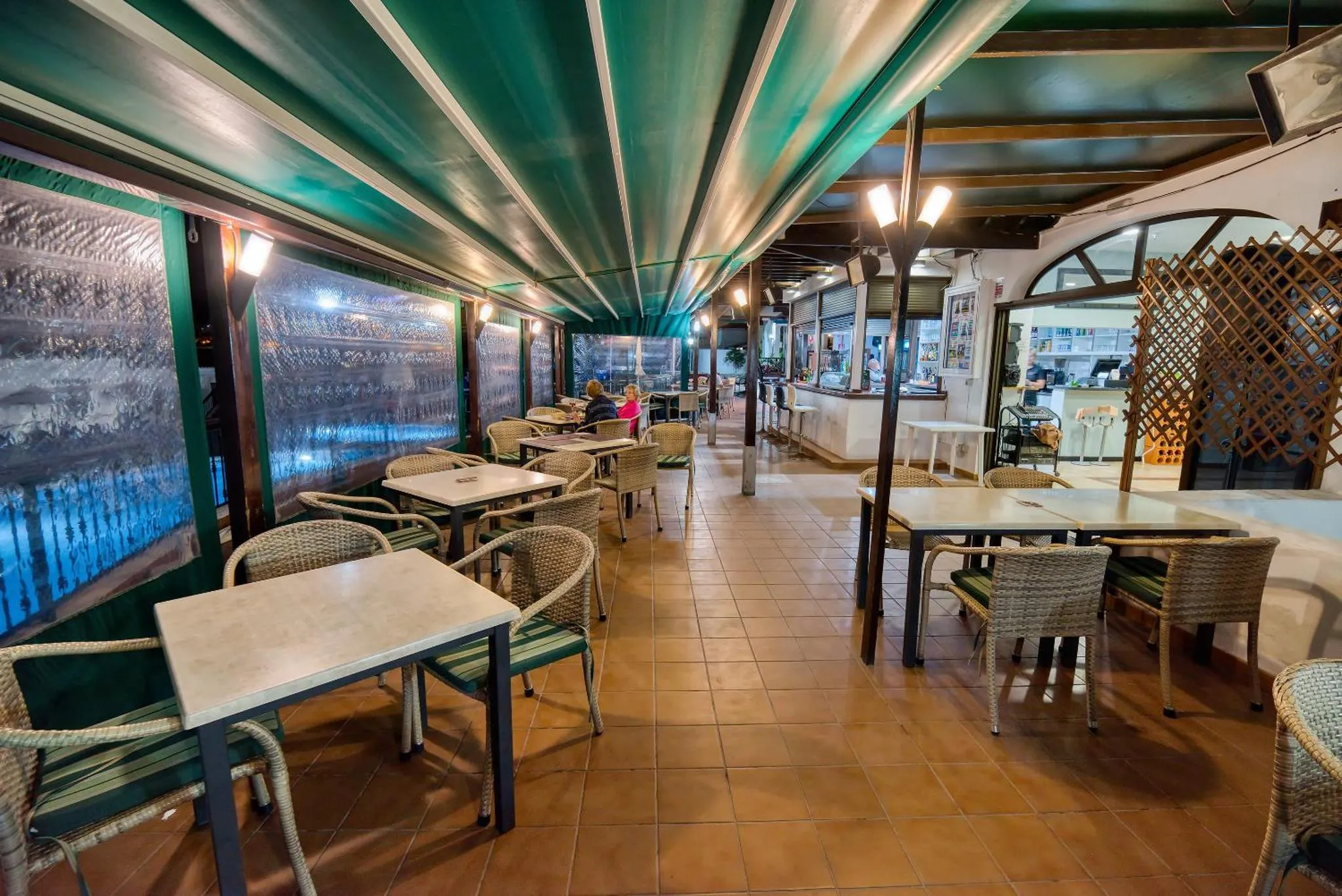 Une salle à manger extérieure avec des tables et des chaises sous une marquise.