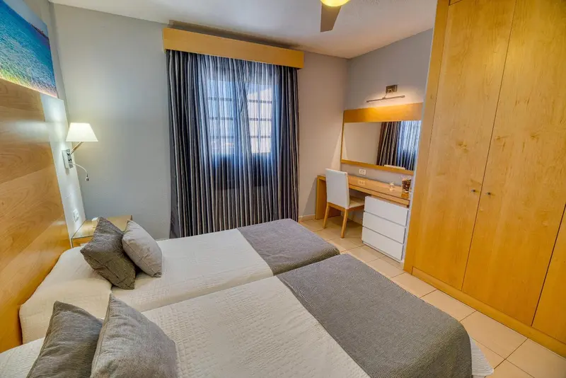 Une chambre lumineuse avec un lit double et un espace coiffeuse.