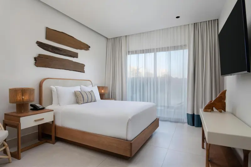 Une chambre lumineuse avec un grand lit et une vue sur l'extérieur.
