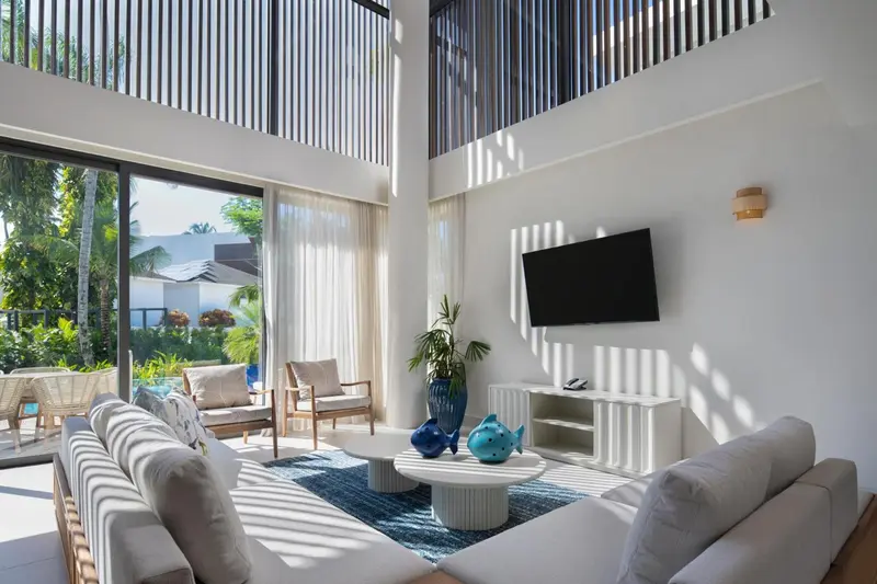 Espace de détente lumineux avec canapés et télévision face à une baie vitrée.