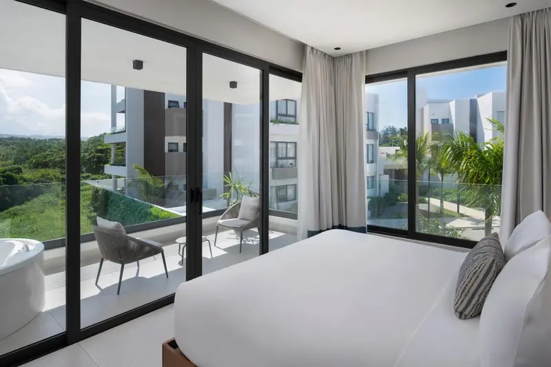 Une chambre lumineuse avec un grand lit blanc et un accès à une terrasse.